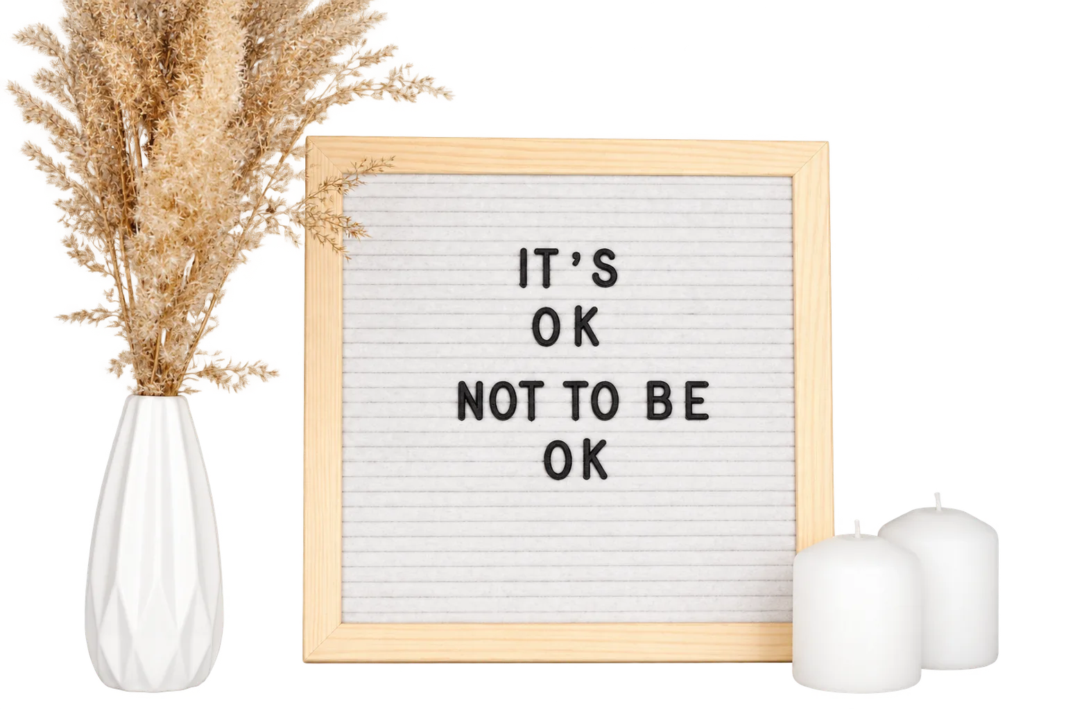 A letterboard reading It’s OK not to be OK, beside a vase and candles