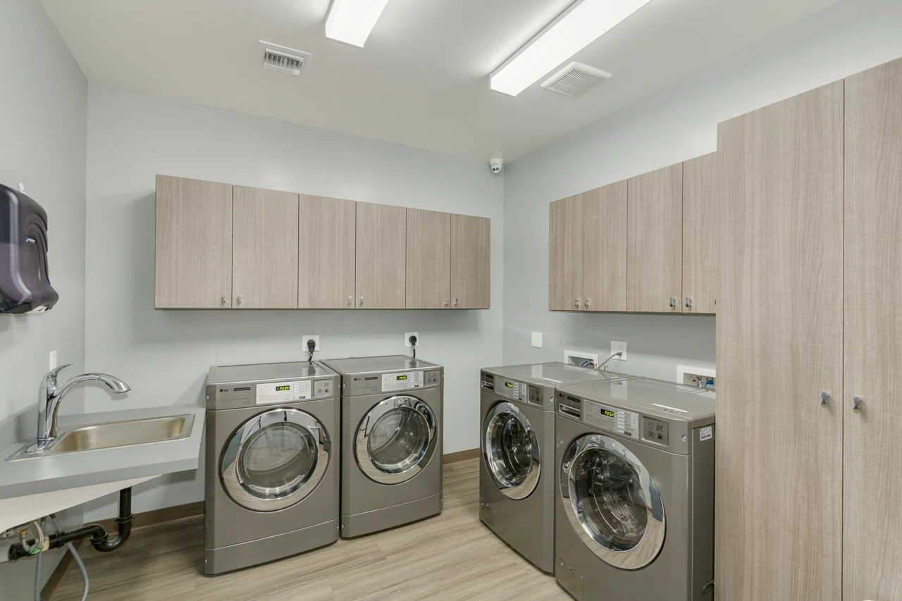 On-site laundry room with washers, dryers, and storage